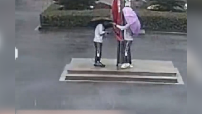 狂风暴雨中，两名中学生冲向升旗台护国旗