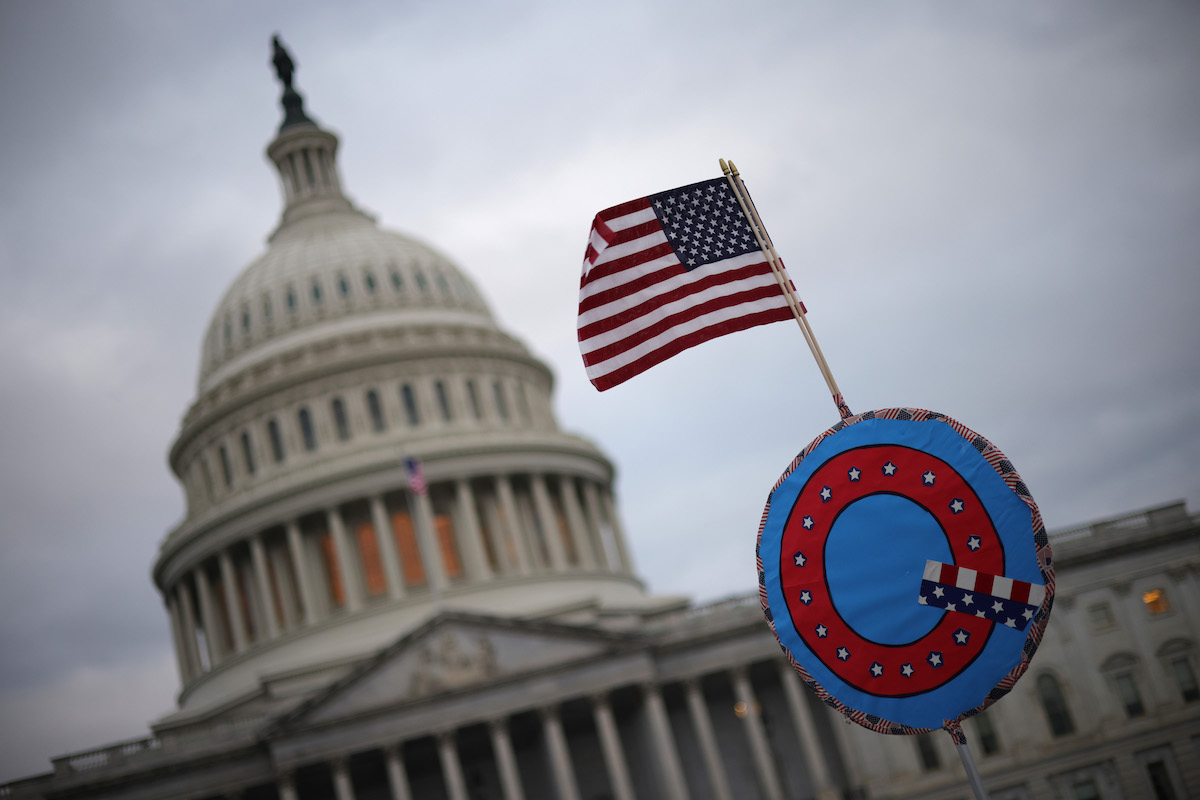 当地时候2021年1月6日，美国华盛顿，美国总统特朗普的撑持者在美国国会大厦外汇注，他们挥舞着带有QAnon组织标记的美国国旗。