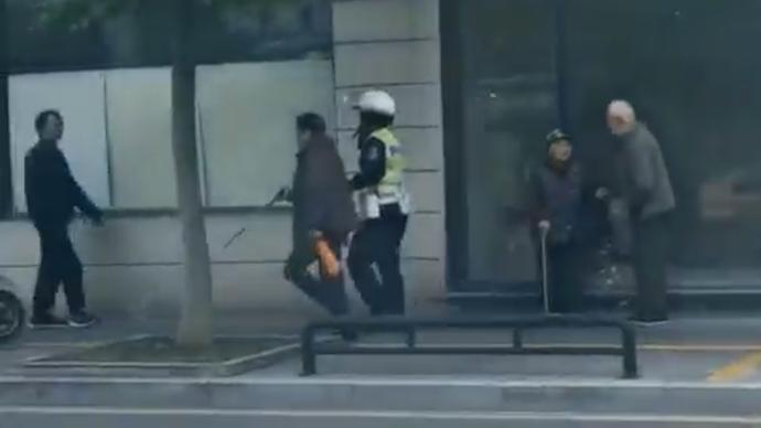 視障老人拄拐棍往路中央走，輔警一路小跑將其領(lǐng)過馬路