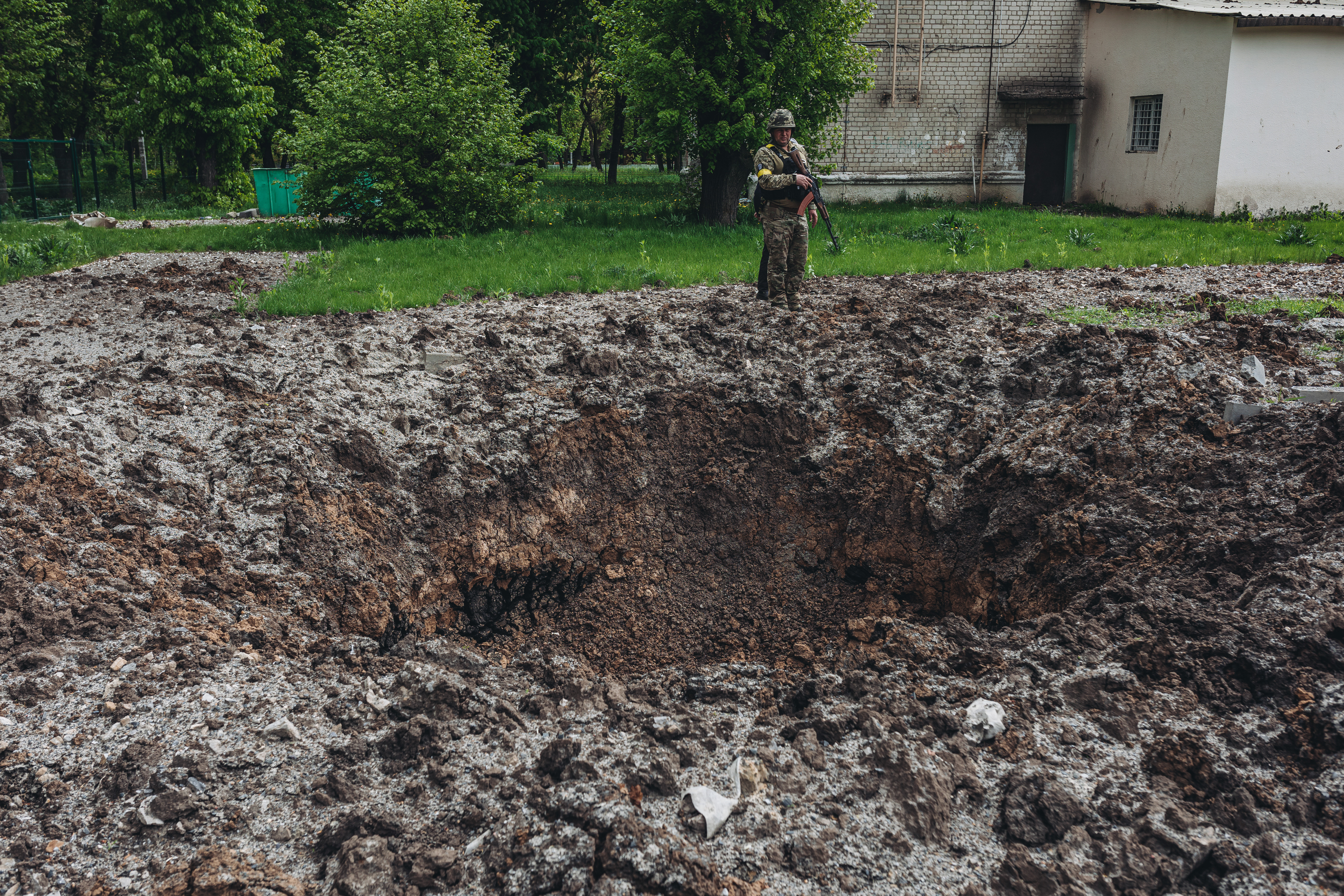 当地时间2022年5月10日，乌克兰哈尔科夫，一名乌克兰士兵站在弹坑前。 视觉中国 图