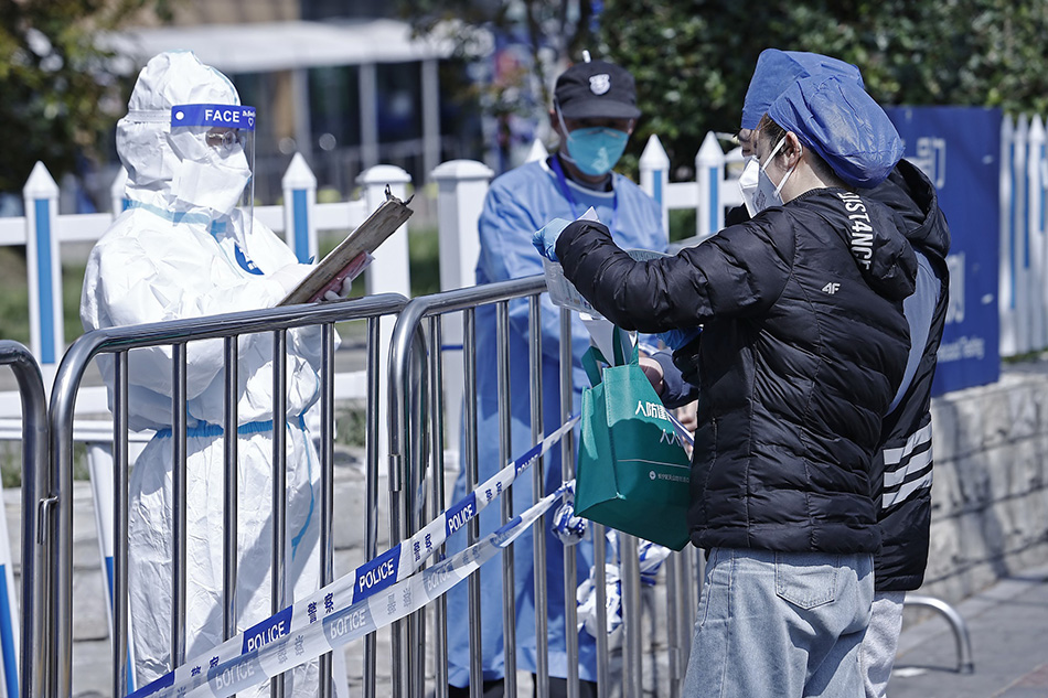 2022年4月2日，隔着栅栏，社区工作人员为在封闭管理中的患者来到上海市同仁医院开药。中新社记者殷立勤/澎湃影像 图