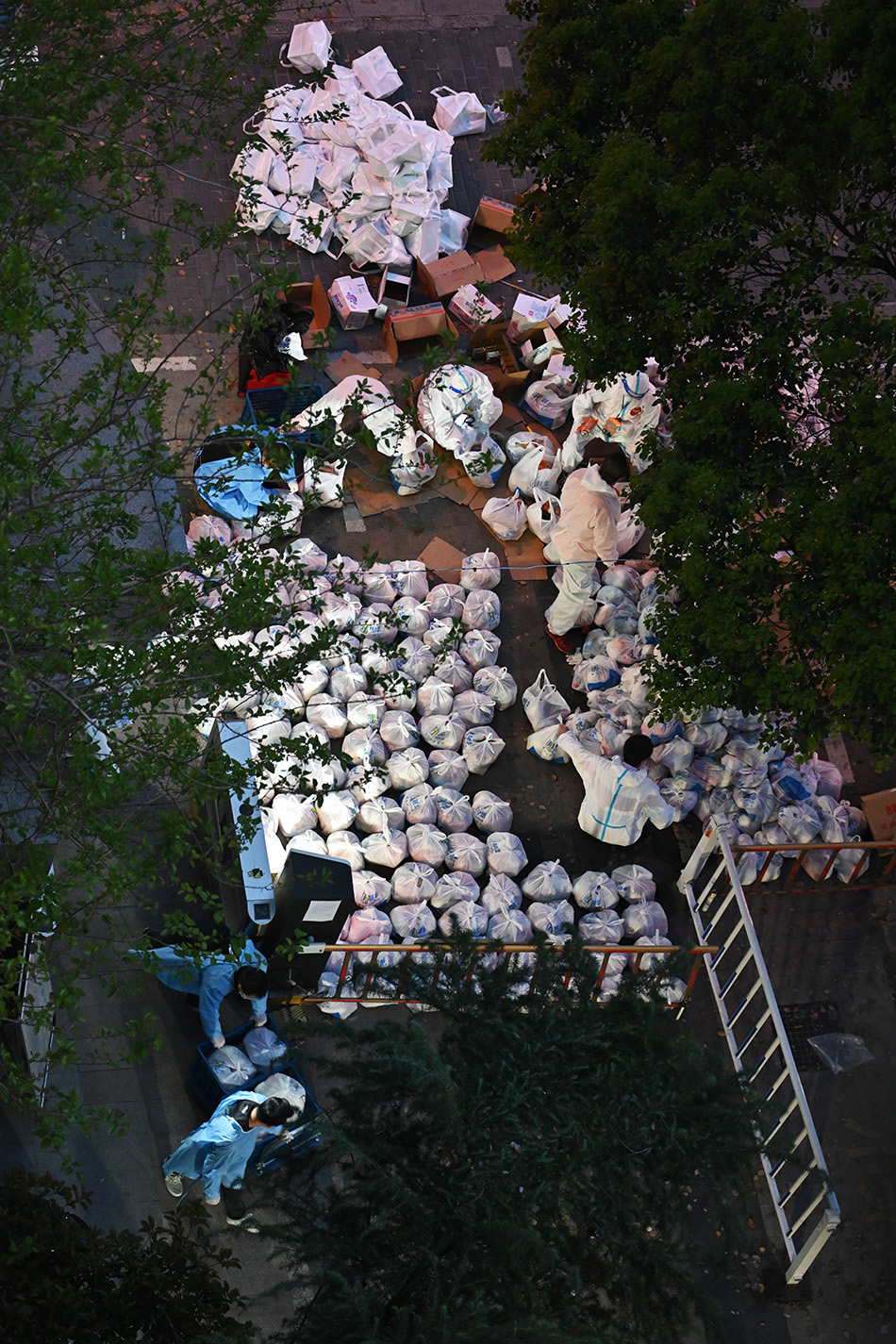 2022年4月5日晚，上海，四川北路街道的某封控小区大门口，虹口社区工作者和本小区志愿者们连夜将一包包菜分类运送到居民家门口。澎湃新闻 高剑平 图