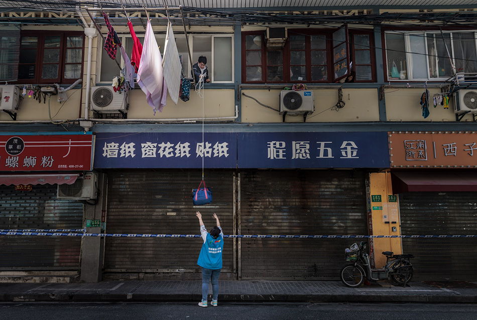 2022年3月29日，上海，志愿者通过绳子向一名被隔离的市民传递生活物资。澎湃影像 图