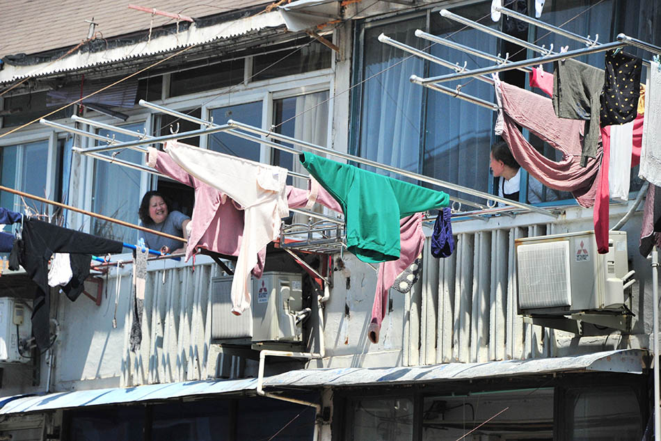 2022年4月11日，上海，在杨浦区的一处封控小区里，两位邻居阿姨趁着早上晾晒衣物，隔着阳台聊会天。杨建正/人民视觉 图