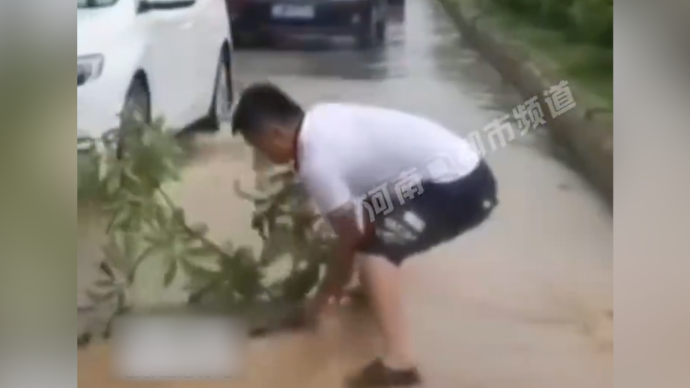 男子冒雨盖上井盖并捡来树枝做上标记