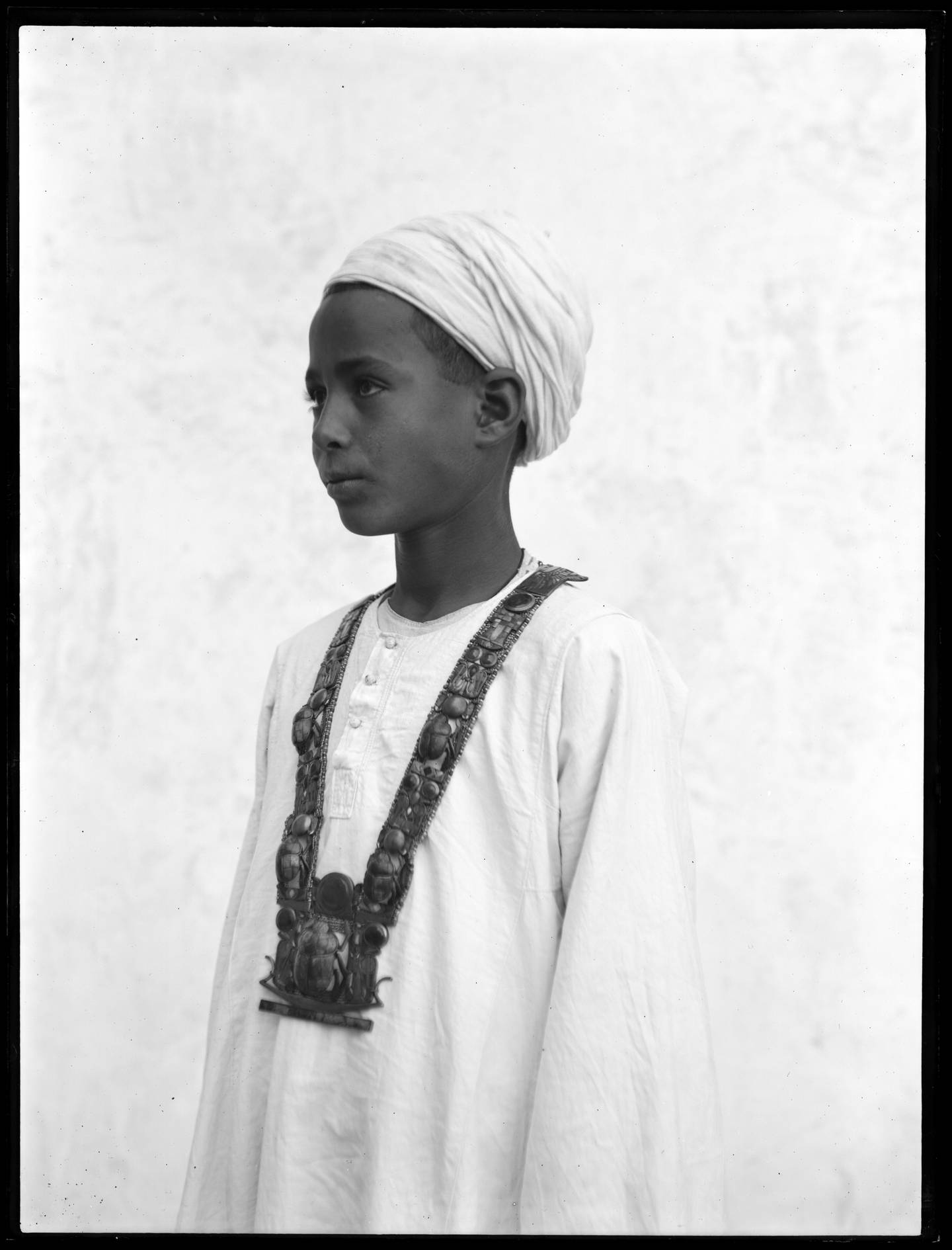 一个埃及男孩的照片，他戴着一条来自坟墓的沉重项链。© 牛津大学格里菲斯研究所