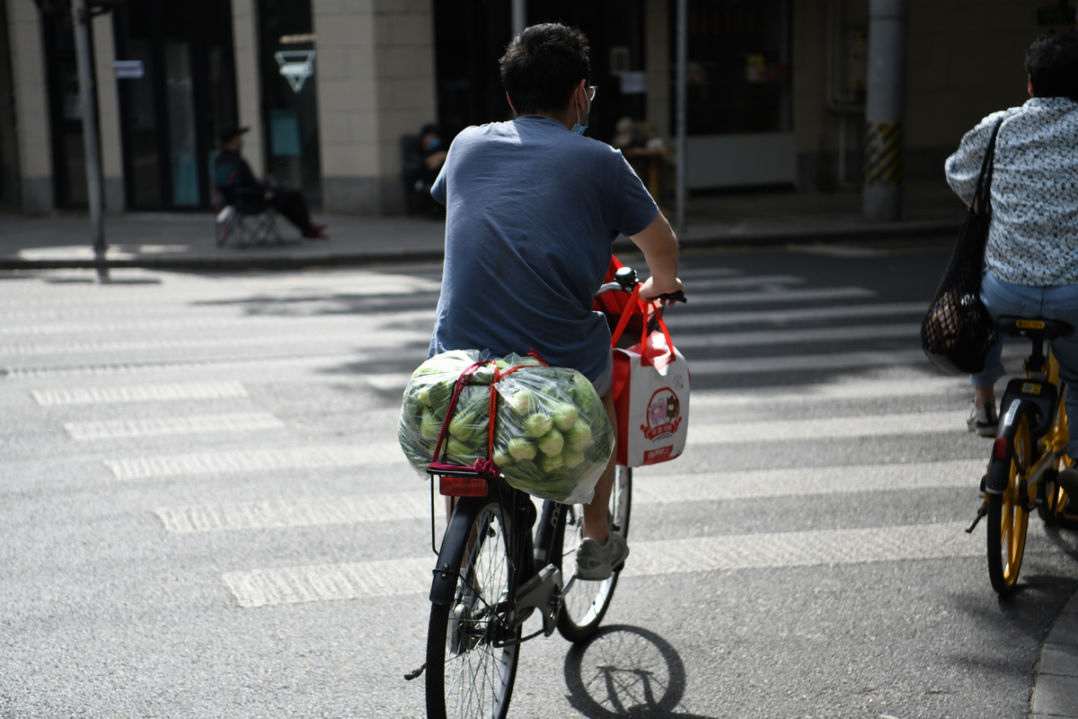 市民骑车购物经过武康路沿线，车座上绑着一捆青菜