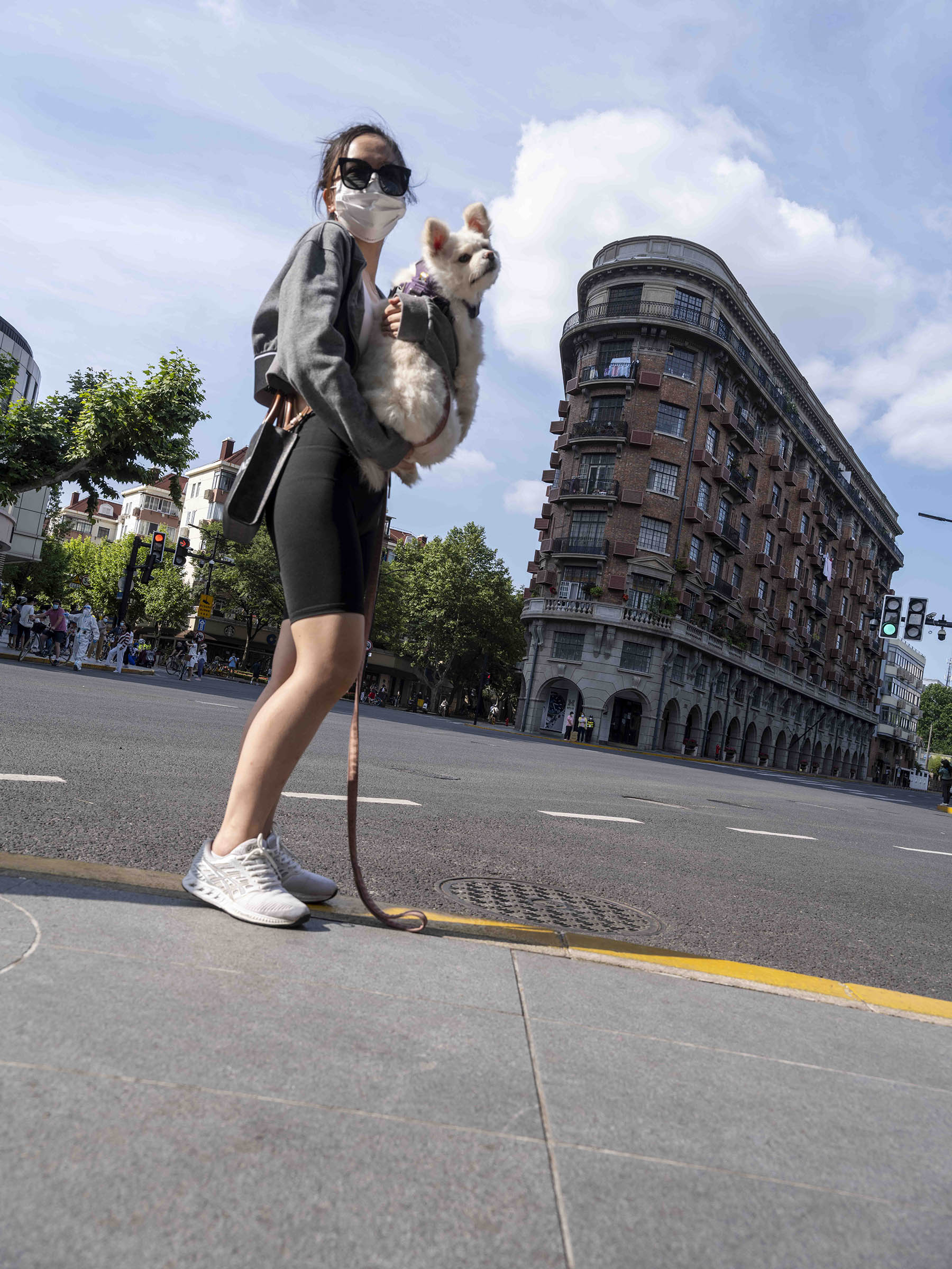 2022年5月21日，武康大楼前，抱着狗拍照的女孩。