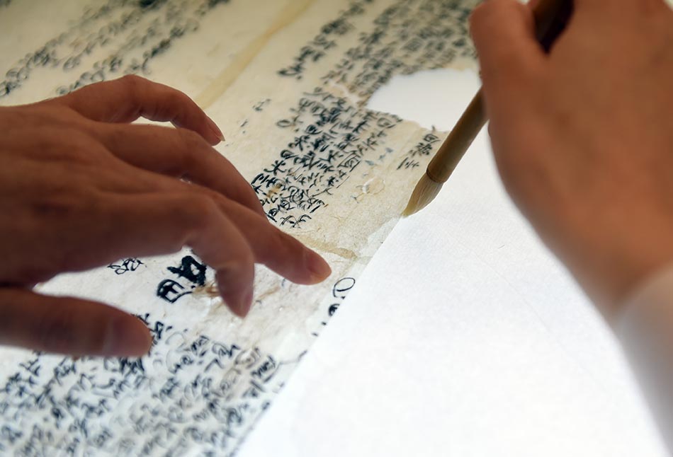 2022年5月17日，在安徽博物院文物科技保护中心纸质文物修复室，工作人员对古籍文物进行补全。周牧/新华社 图