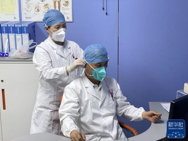 5月17日，在浦东新区北蔡社区卫生服务中心办公室，郭海英（左）为马俊岭整理帽子。  新华社 图