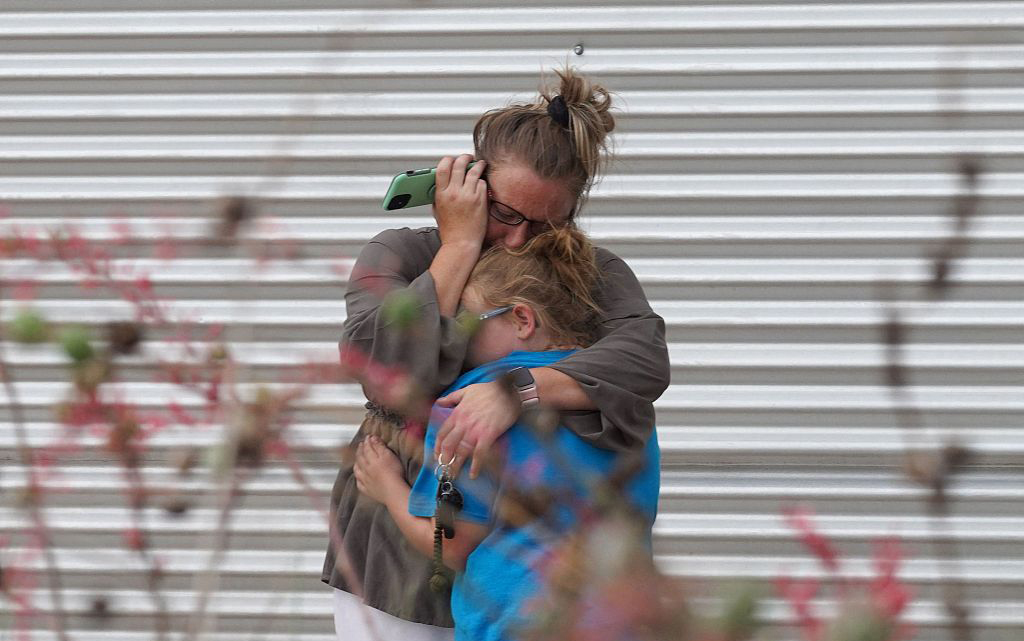 当地时间2022年5月24日，在威利德莱昂市民中心外，一名妇女抱着受惊吓的孩子。
