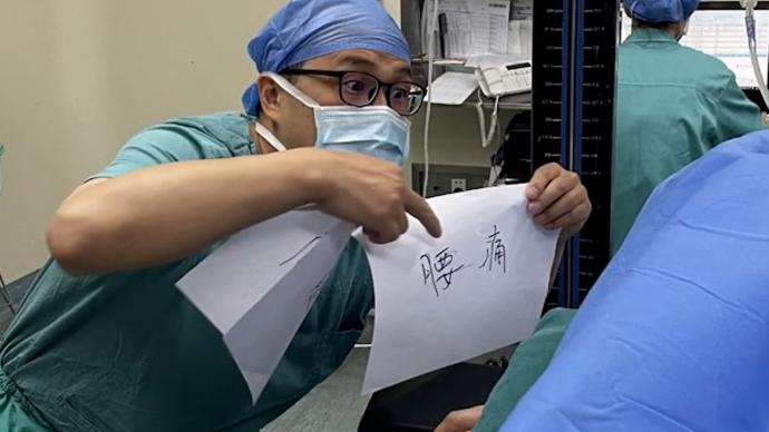 医生半蹲举纸条与听障患者沟通直到手术结束