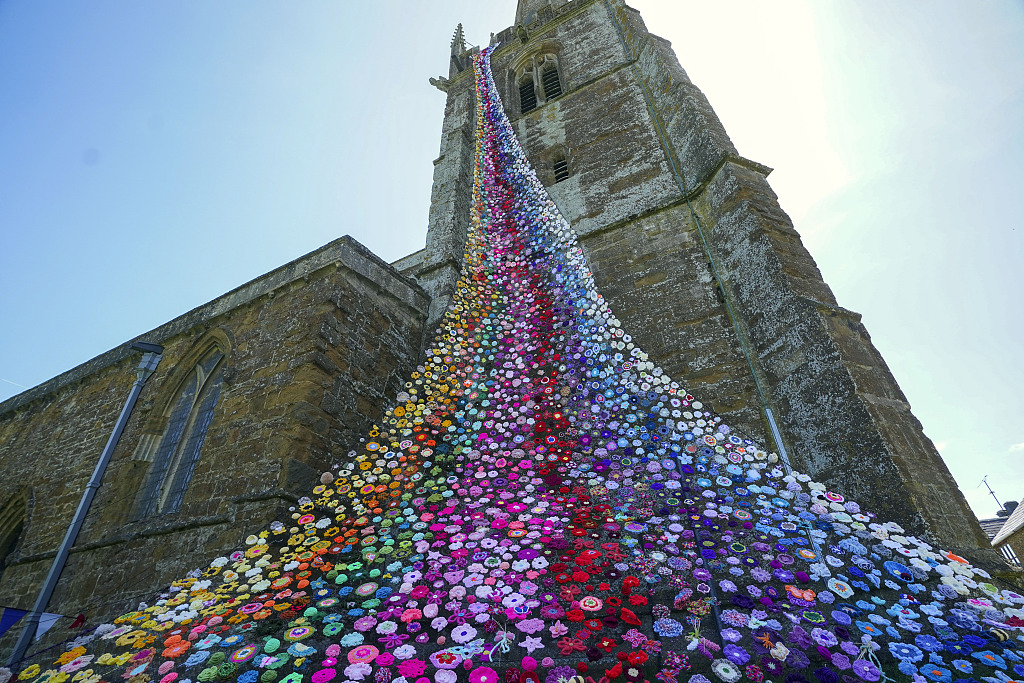 当地时间2022年5月27日，英国米德尔顿切尼，教堂上超过4300朵羊毛花像瀑布一样垂下来，迎接英国女王伊丽莎白二世“白金禧年”庆典。