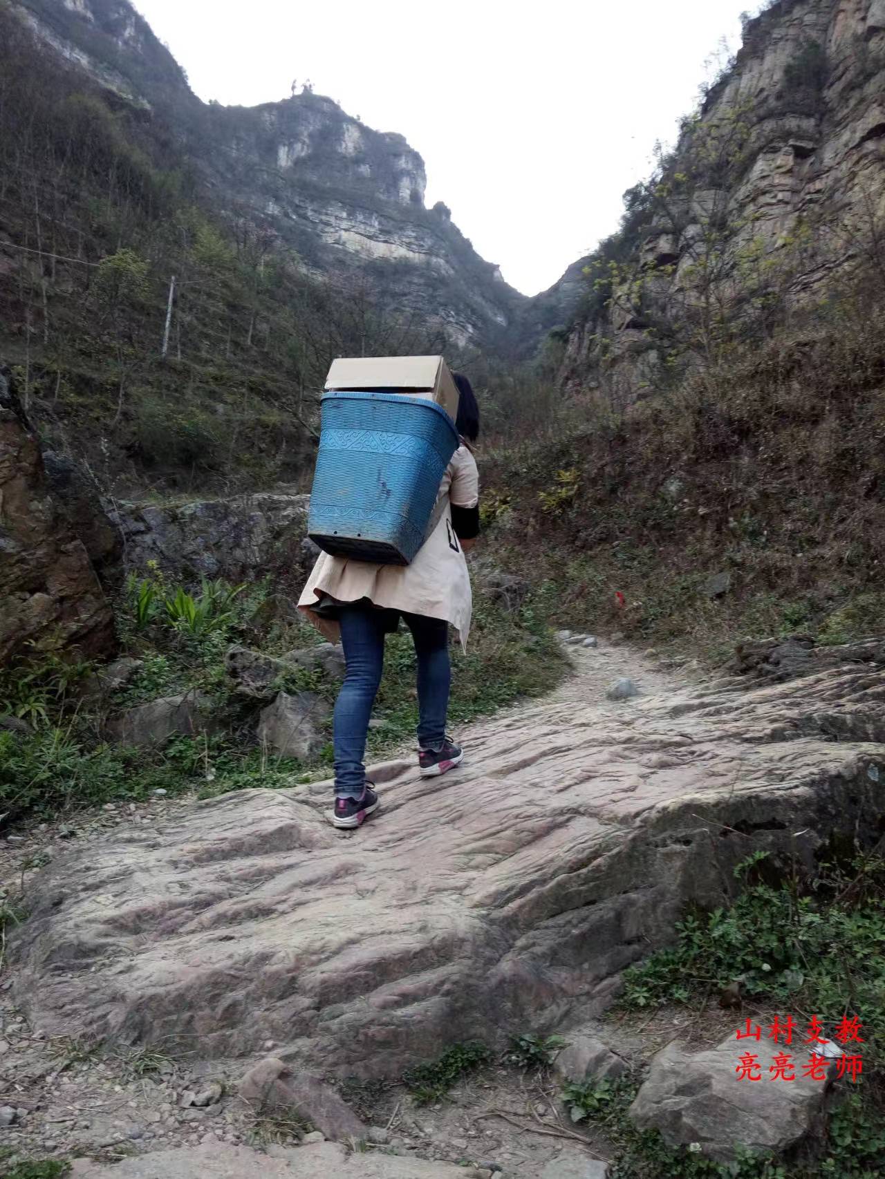 侯长亮妻子雷宇丹，也是他同事，从山脚把爱心人捐的课外书背回山上的学校。来回一趟需要3个多小时。