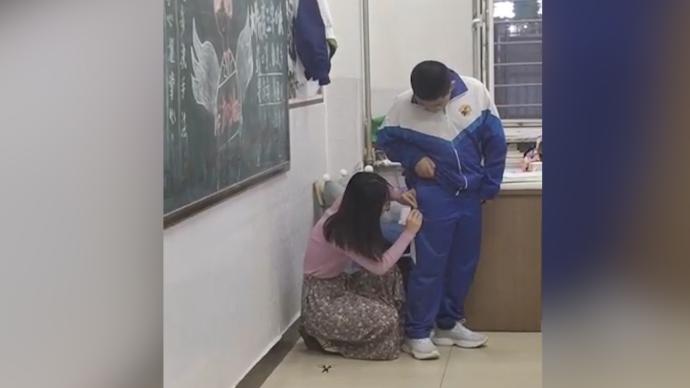 看到學(xué)生校服破洞，老師蹲下小心翼翼縫補(bǔ)