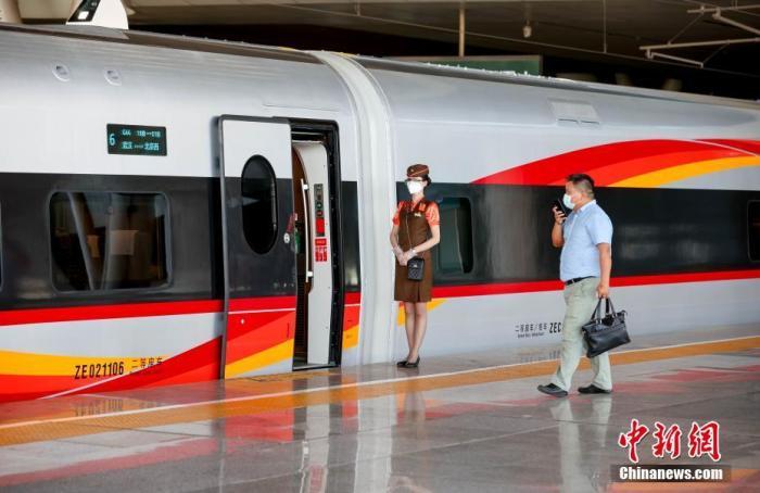 6月20日，武汉开往北京西的G66动车组列车乘务员正在迎接旅客上车。中新社记者 张畅 摄