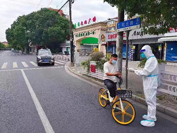 身穿大白服的上海市闵行区七宝镇城运中心督察员姚勰鑫（右）在“扫街”。受访者供图