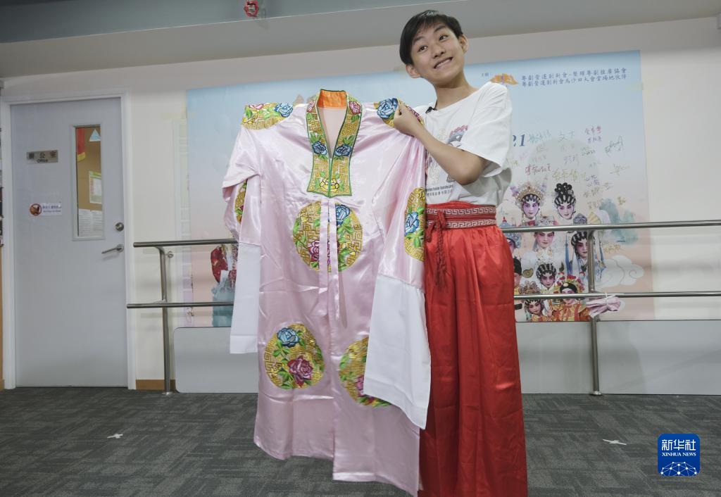 香港粵劇小演員利文喆展示當年給習爺爺表演時穿的戲服，一件粉色底上繡有紅藍色團花的披風（5月29日攝）。 新華社記者 王申 攝