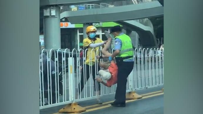 男子被卡马路中央护栏，交警叫来外卖小哥合力抬下