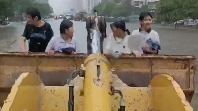 河南安阳暴雨后道路积水，男子开铲车救援多名市民