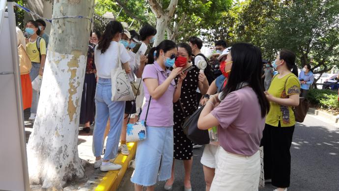 上海高考丨外语考试考场外，家长手持纳凉小工具送考