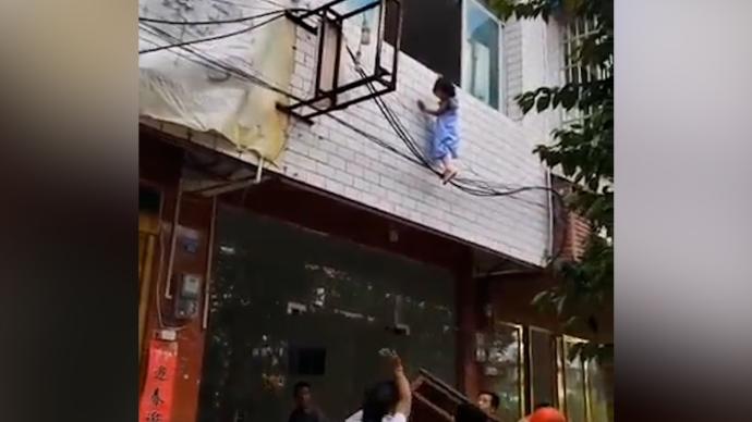 小女孩掛在外墻搖搖欲墜,群眾搭人梯救援
