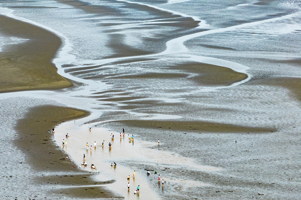 2022年7月16日,江苏南通,市民和游客在黄金海滩风景区内的黄海滩涂上