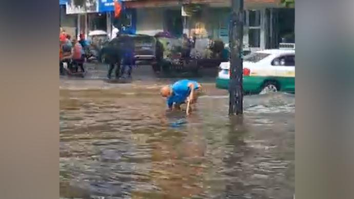 暴雨过后路面积水，七旬大爷徒手清理路面排水口