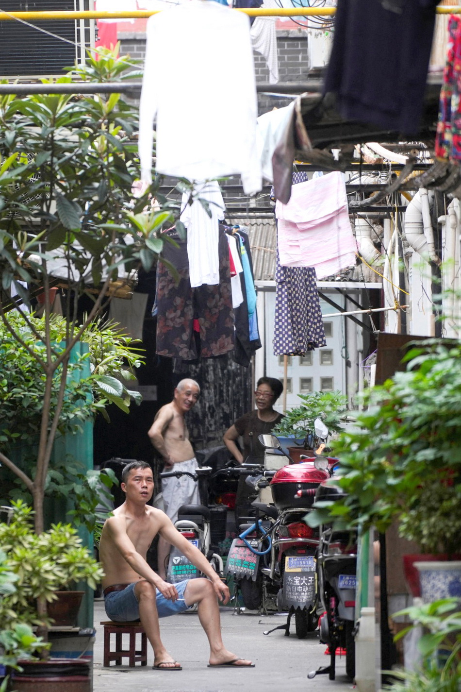Topless men are seen at a residential area amid a heatwave warning in Shanghai, China July 25, 2022.7123815790356693004.jpg