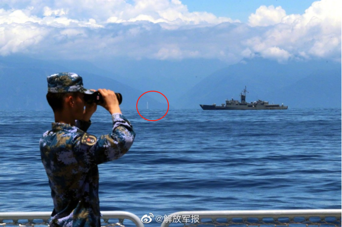 《解放军报》发布的军舰航行照片也引发热议，海岸线上的白色柱状建筑物依稀可见（红圈处）。本文图片 @解放军报