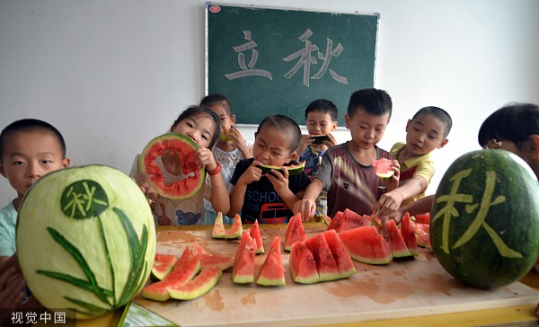 小朋友们在吃西瓜“啃秋”迎接立秋的到来。视觉中国 图
