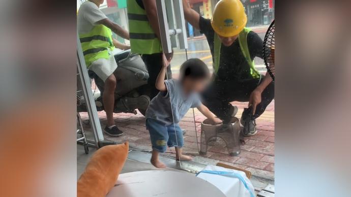 工人站在店外避雨，2岁萌娃给他们搬椅子