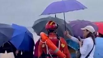 观潮游客为雨中执勤消防员打伞