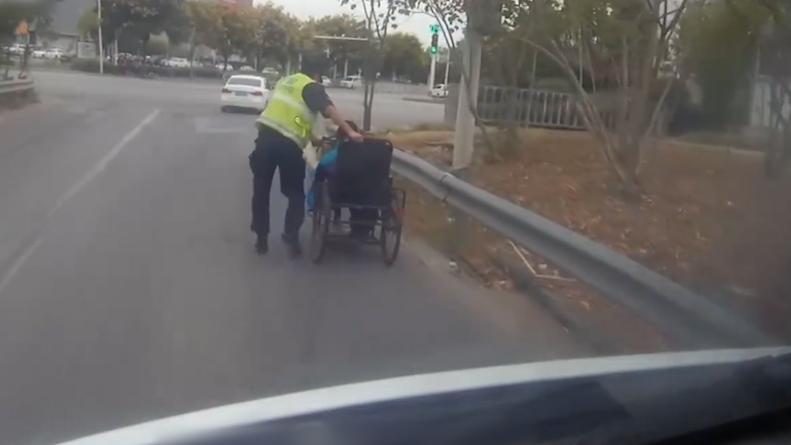 残疾人驾驶三轮车行驶在高架桥上，民警推着车护送至安全路面