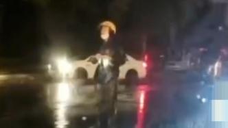 外卖小哥雨夜引导交通，提醒过往车辆避开积水路段