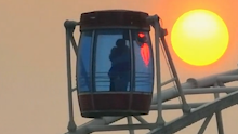 摄影师无意中拍到夕阳下摩天轮中情侣相拥