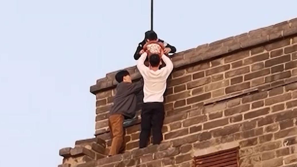 男孩被困十米高城墙，两小伙徒手攀爬救人