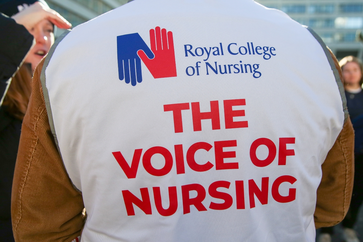 当地时间2023年2月6日，英国伦敦，在威斯敏斯特圣托马斯医院外，一名皇家护理学院的成员穿着一件背心，上面写着“护理之声”。