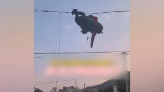 男子玩滑翔伞不慎挂电线上，村民搭梯子营救