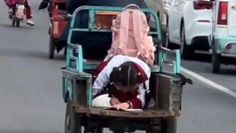 山东烟台一女孩趴在三轮车后斗写作业