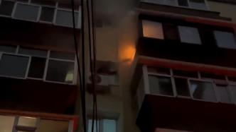 5楼邻居家着火，男子脚踩窗台帮扑救