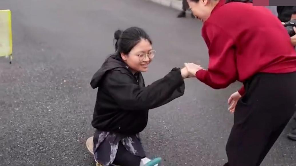 無腿女孩坐著滑板參考,周圍人群自發為她加油