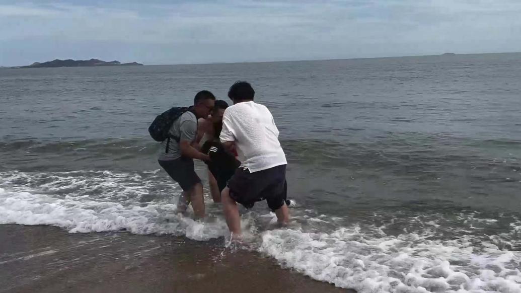 男子游玩时不慎被海水卷走，好心人携手救上岸