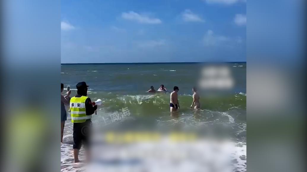 海水浴场工作人员拿着喇叭喊话下海游客尽快上岸