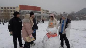 语文老师将课堂搬至室外，带学生在操场堆雪人