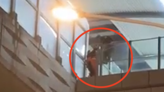 女子站在武汉地铁站护栏外疑似欲轻生，消防员越过栏杆救人