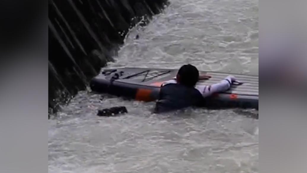 漂流不慎掉进水里，男子抱着桨板在激流中等救援
