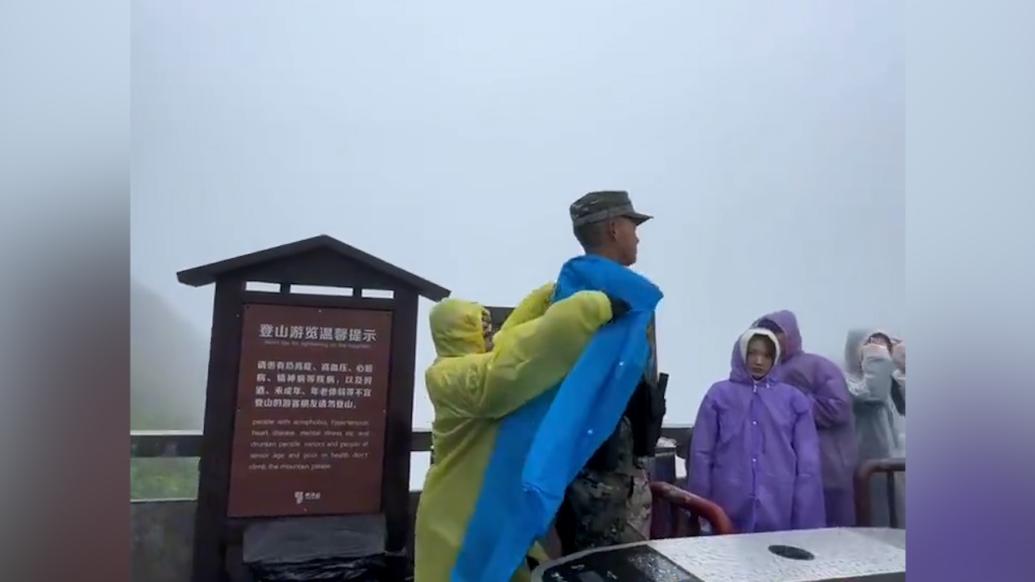 游客为雨中站岗武警穿雨衣