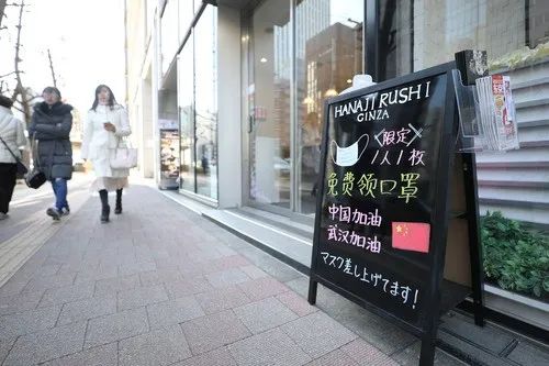2月11日，在日本东京，银座的一个商铺门前的招牌上写着免费赠送口罩和为中国武汉加油鼓劲的内容。新华社记者 杜潇逸 摄