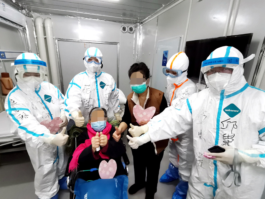 3月1日，98岁的新冠肺炎危重症患者胡婆婆（坐轮椅者）和女儿出院时，与武汉雷神山医院医护人员合影（手机拍摄）。  新华社 图